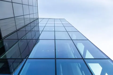 The blue sky is reflected in the windows of a modern office building Stock Photos