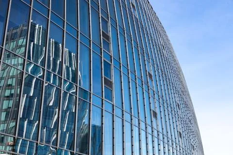 The blue sky is reflected in the windows of a modern office building Stock Photos