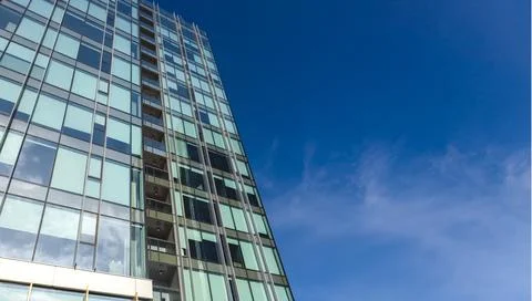 The blue sky is reflected in the windows of a modern office building Stock Photos