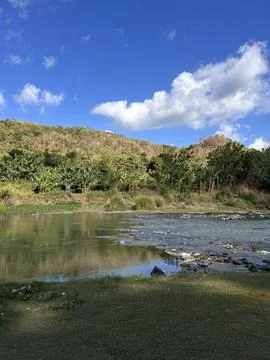 Blue sky reflects in calm river waters Stockfoto's