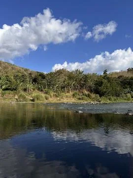 Blue sky reflects in calm river waters Stock Photos