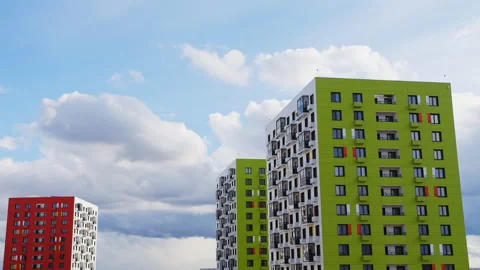 Blue sky with running clouds on the background of multi colored high house Stock Footage 132284283