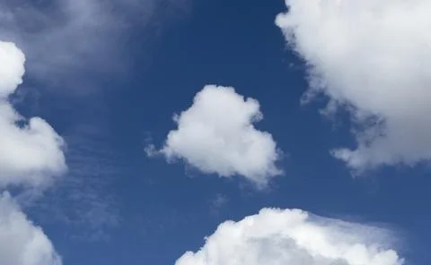 Blue sky with scattered white clouds. Soft cloud formations spread across a Stock Photos