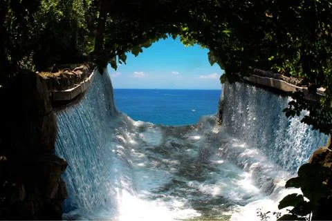Blue sky seen through a waterfall and green anchor of tree branches hanging Stock Photos