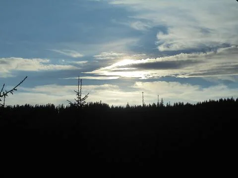 Blue sky with several clouds,with a dark cloud covering the sun. Stock Photos