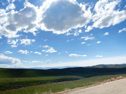 Blue sky with some clouds over green fields and hills. Stock Photos