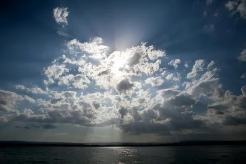 Blue sky with sun and dramatic clouds Stock Photos