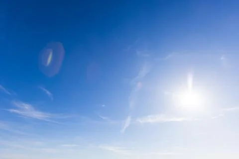 Blue sky with the sun shining, clouds and subtle lens flare Foto stock
