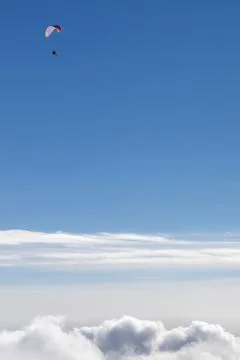 Blue sky with sunlight clouds and silhouette of paraglider Stock Photos