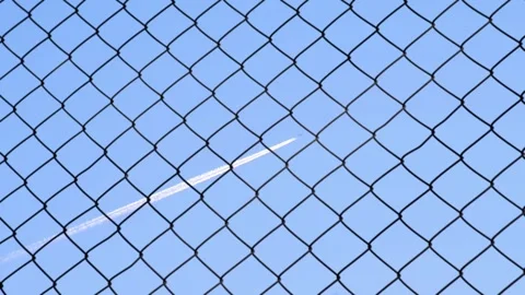 Blue Sky Through Chain Link Fence with faint airplane contrail Stock Footage 320288520