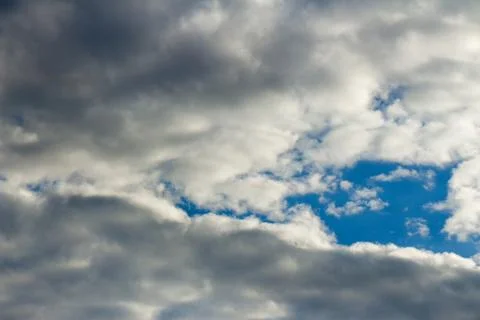 Blue sky is visible through thick gray clouds Stock Photos