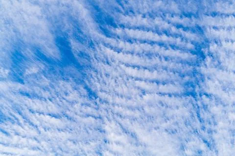 Blue sky on which white clouds dissipate in stripes under influence of wind.. Stock Photos