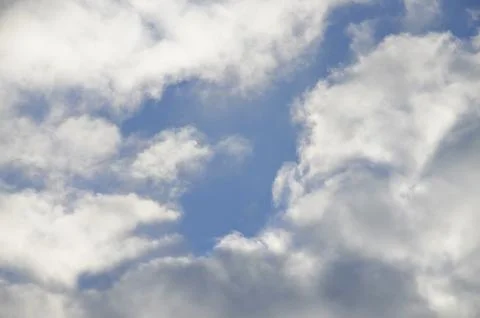 In the blue sky, white and clouds. The sun illuminates the clouds. Stock Photos