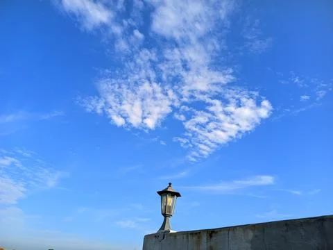 Blue Sky with White Clouds Above Outdoor Lamp and Concrete Wall. Stock Photos