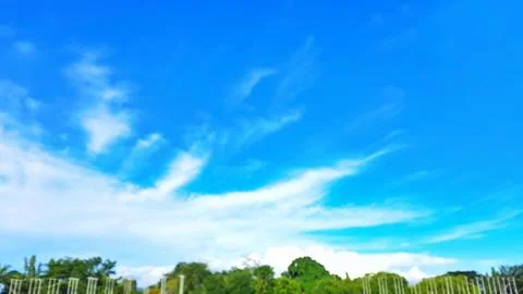 Blue sky with white clouds and green trees in the park background. Stock-Fotos