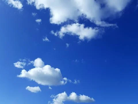 Blue Sky with White Clouds Background. Puffy cumulus clouds. Sunbeams. Stock Photos