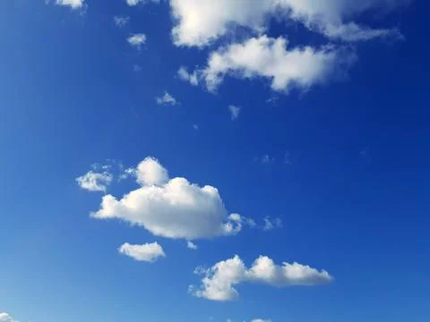 Blue Sky with White Clouds Background. Sunbeams illuminating the clouds. Stock Photos