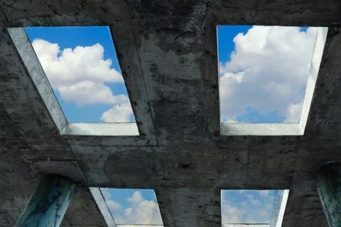Blue sky with white clouds can be seen through the windows in concrete building. Stock Photos