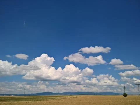 Blue sky with white clouds. Field with electric polls. Stock Photos