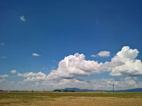 Blue sky with white clouds. Field with electric polls. Stock Photos