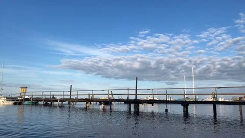Blue sky, white clouds over blue sea. Wood pier Stock Footage 80356353