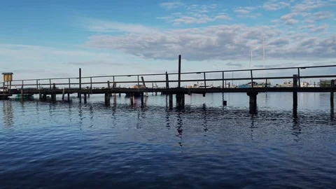 Blue sky, white clouds over blue sea. Wood pier Stock Footage 80356593