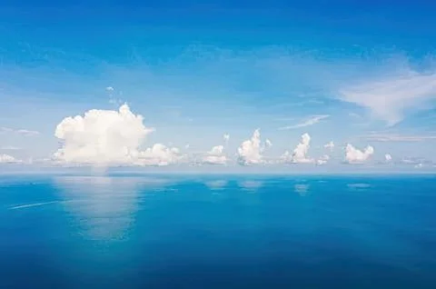 Blue sky with white clouds over calm ocean water Stock Photos