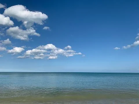 Blue sky with white clouds, small sea shores and beach of little stones Fotos de archivo
