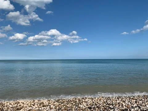 Blue sky with white clouds, small sea shores and beach of little stones Fotos de archivo