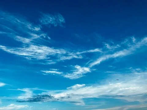 Blue sky with white clouds. Small silhouette of the plane gaining Stock Photos