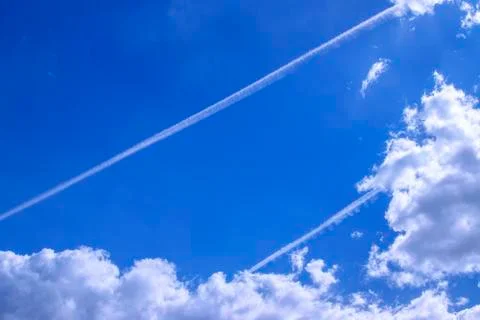 Blue sky with white clouds, two parallel tracks from airplanes. Stock Photos