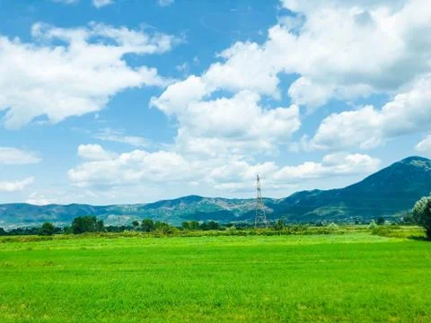 Blue sky, white clouds. View to green farming fields in the valley in Albania Stock Photos