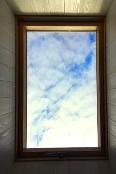A blue sky with white clouds is visible through the roof window. Foto stock
