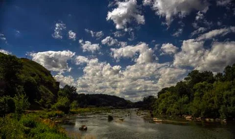 In the blue sky, white fluffy clouds over the river. Stock Photos