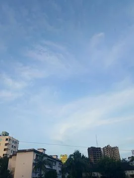 Blue sky with wispy clouds above residential buildings and tropical palm tr.. Stock Photos