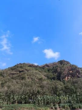 Blue sky with wispy clouds above green hillside Stock Photos