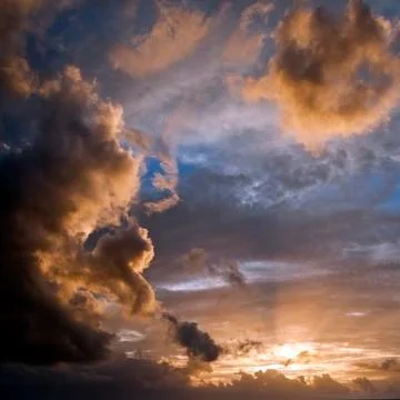 Blue sky with yellow backlit clouds coming from the sun that is shining throu Stock Photos