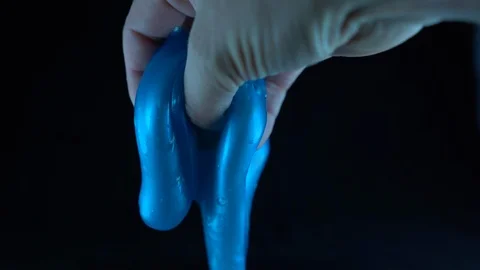Blue slime oozing though fingers infront of black background Stock Footage 127296147