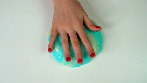Blue slime on a white table and a girl hand showered with sparkles Video stock 127597070