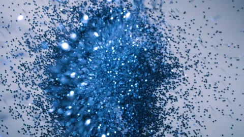 Blue sparkle glitter falls onto white paper background in slow motion, 2 clips Stock Footage 153917954