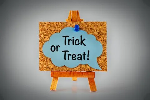 Blue speech bubble with phrase Trick or treat on corkboard on wooden easel. Stock Photos