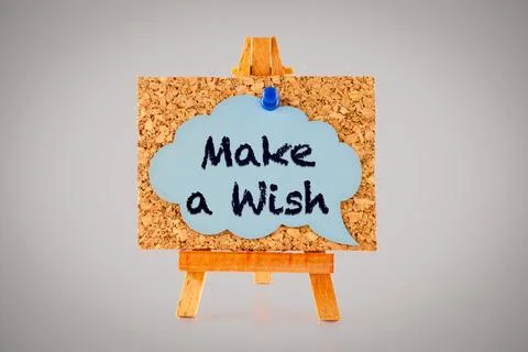Blue speech bubble with words Make a Wish on a corkboard on a wooden easel. Stock Photos