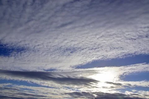 The blue spring sky is covered with light white cirrostratus clouds. Stock Photos