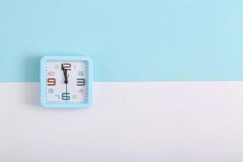 Blue square clock on wall with blue and white background Stock Photos