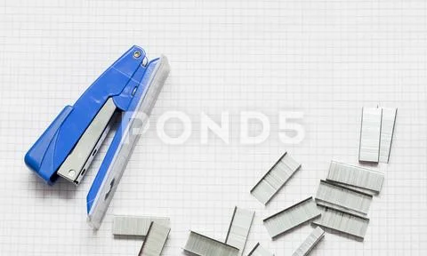 Blue Stapler and Piles of office Staples on Piece of Paper, Closeup Stock Photos