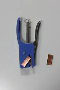 A blue stapler with a piece of copper Stock Photos