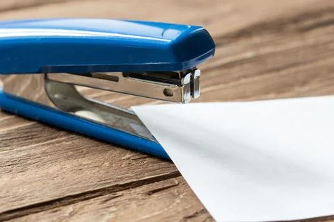 Blue stepler and paper sheet on wooden background Stock Photos