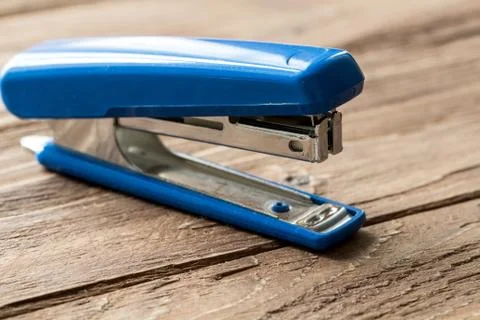 Blue stepler on wooden background Stock Photos