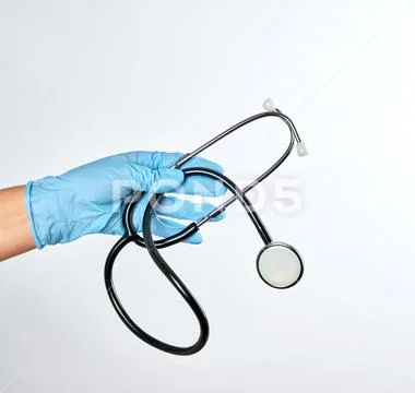 Blue sterile gloved hand holding a green stethoscope Stock Photos