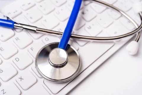 Blue stethoscope on computer keyboard on white table background. Online medic Stock Photos